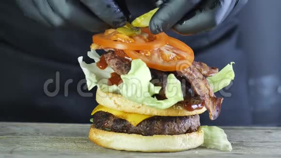 一个大汉堡有蔬菜和芝麻面包的双切口形成汉堡的过程黑厨师视频的预览图