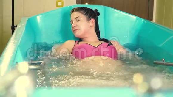 一个胖女人躺在浴缸里在水中按摩时有泡泡视频的预览图