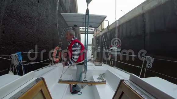 甲板上的高级船长帆船准备通过船闸视频的预览图