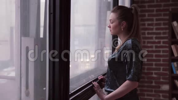 悲伤的女人看着窗外的城市街道视频的预览图