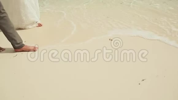 新娘和新郎光着脚沿着海滩走进大海视频的预览图