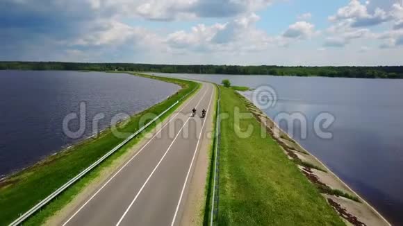 4K两个朋友骑摩托车旅行美丽的道路在水中央航拍全景视频的预览图