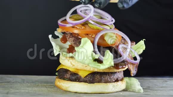一个大汉堡有蔬菜和芝麻面包的双切口形成汉堡的过程黑厨师视频的预览图