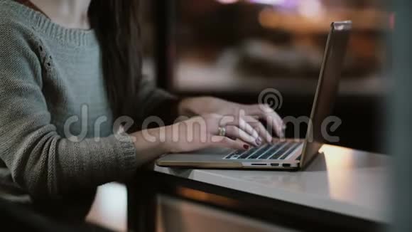 女性手在笔记本电脑键盘上打字的特写年轻的女人坐在桌子上工作视频的预览图