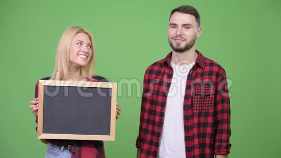 一对年轻夫妇拿着黑板手指并举视频的预览图