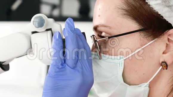 一位戴眼镜的妇女带着一位专业的牙医在她的口腔显微镜下工作视频的预览图