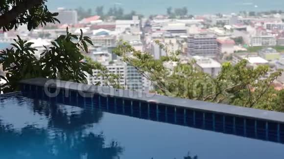 无限泳池俯瞰城市天际线彩色房屋和酒店树木海洋和天空的美景视频的预览图