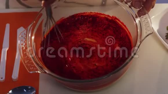 在玻璃锅中用手搅拌红色和白色物质使其变成橙色视频的预览图