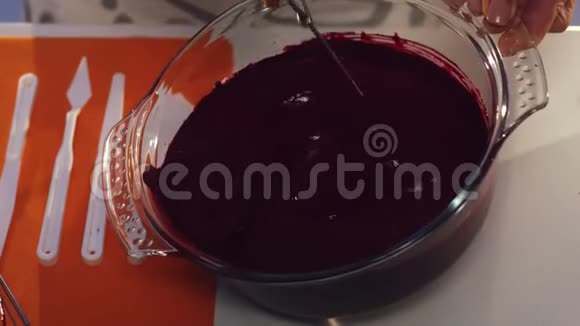 穿着白色和灰色围裙的女人在大玻璃锅里用手搅拌紫色的物质视频的预览图