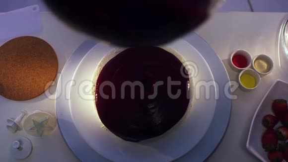 从玻璃锅中滴到盘子里的圆形小蛋糕上的紫罗兰色视频的预览图