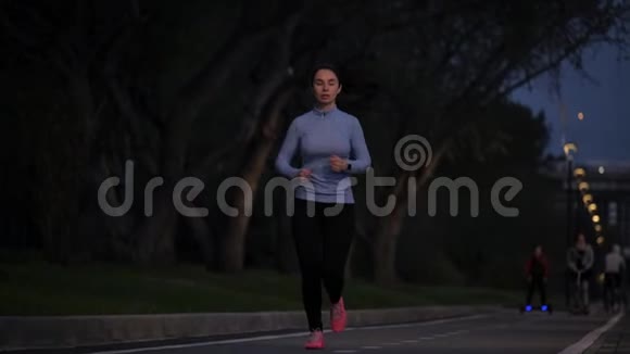 穿运动服的年轻女孩深夜在公园慢跑户外运动慢动作视频的预览图