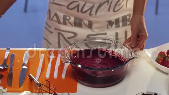 紫罗兰色的物质正在用大圆形玻璃锅中被人用手搅拌视频的预览图