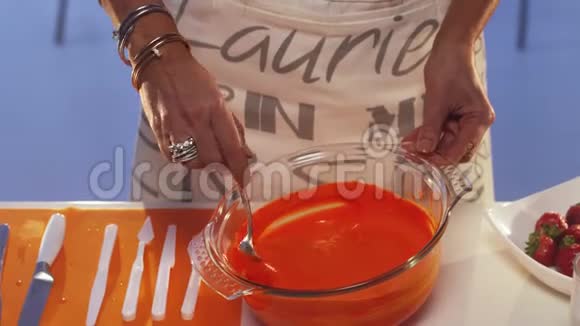 女人在大碗里搅动橙色的物质使它从勺子里滴出来视频的预览图