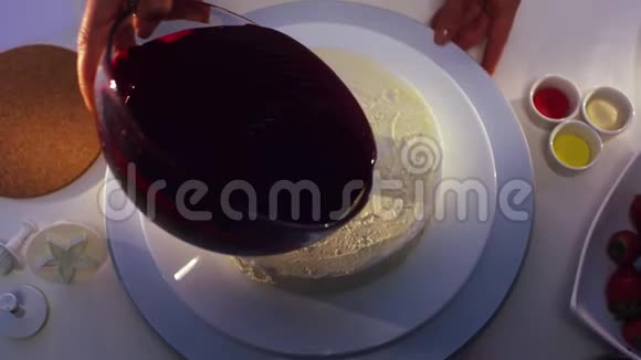 白色蛋糕上覆盖着从大玻璃碗里倒出来的紫罗兰奶油视频的预览图