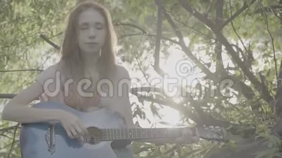 红发女孩在公园里弹吉他彩色侧写博客视频的预览图