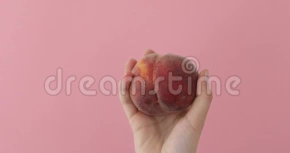 女性手中的果汁桃粉色背景视频的预览图