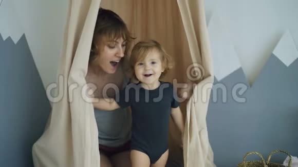 快乐的母亲和可爱的小女儿一起玩耍躲在家门口视频的预览图