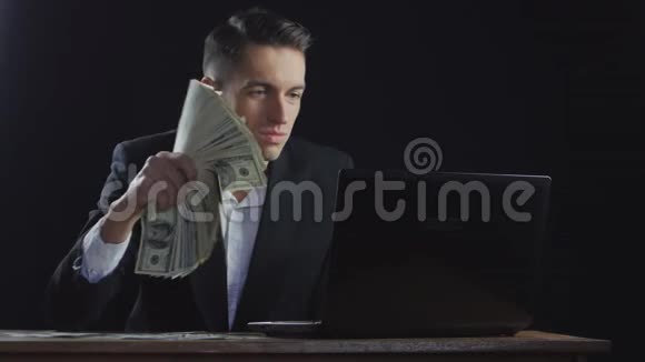 一个年轻的成功商人手里拿着一张叠在手提电脑上的扇子视频的预览图