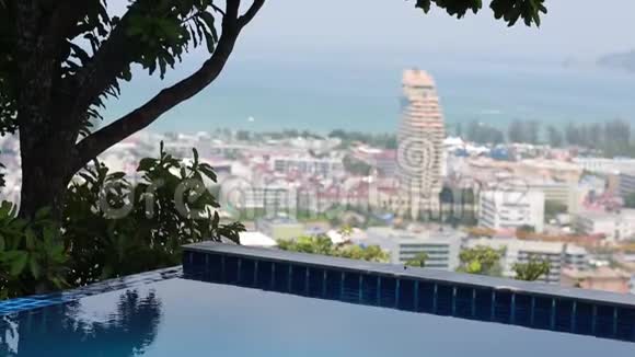无限泳池俯瞰城市天际线彩色房屋和酒店树木海洋和天空的美景视频的预览图