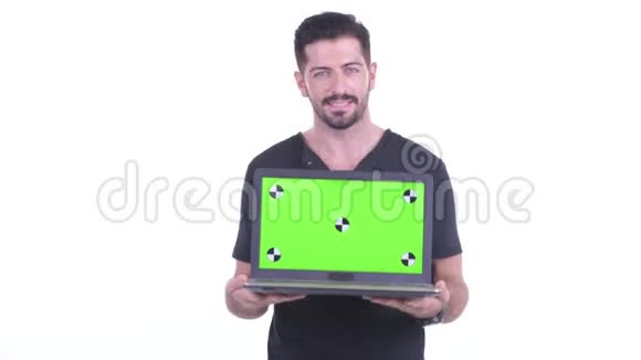 快乐的年轻英俊的大胡子男人一边说一边展示笔记本电脑视频的预览图