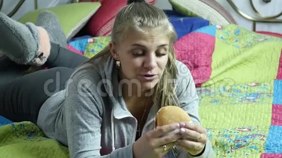 胖女人拿着快餐汉堡咀嚼它吃垃圾食品慢动作视频的预览图