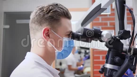 医生戴医用口罩在实验室显微镜中观察视频的预览图