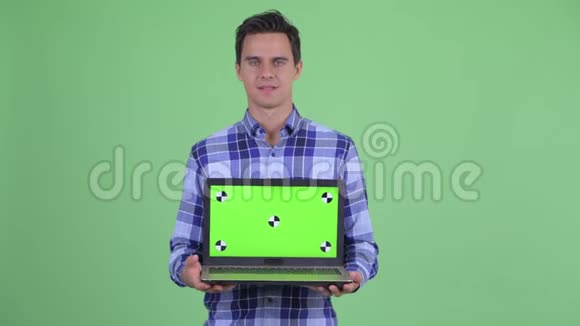 快乐的年轻英俊的时髦男人一边说话一边拿笔记本电脑视频的预览图