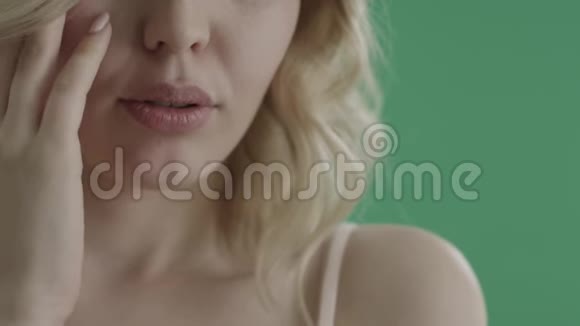 性感的女人嘴唇在绿色的屏幕上抚摸她的脸视频的预览图