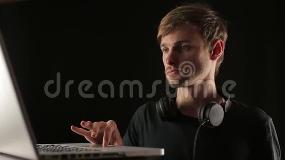 男人戴上耳机在笔记本电脑上设置音乐轨道视频的预览图