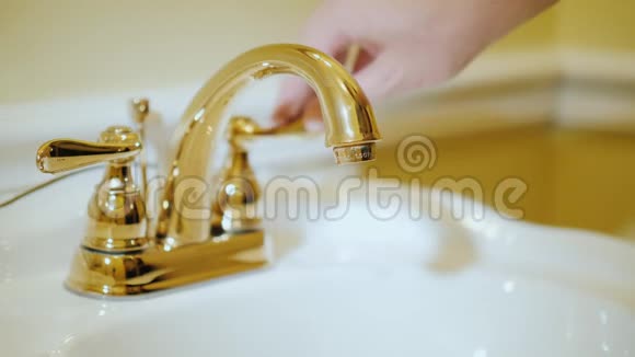 一个人在镀金的水龙头下洗手视频的预览图