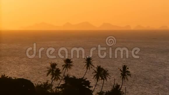 雄伟的热带橙色夏季实时日落海面上有群山的轮廓戏剧性黄昏的空中景色视频的预览图