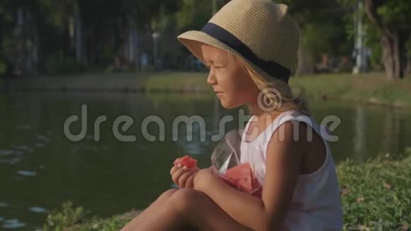 美丽可爱的小女孩高兴地吃西瓜的肖像视频的预览图