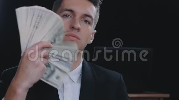 一位年轻自信的商人的特写镜头他的许多美元钞票堆积在扇子里视频的预览图