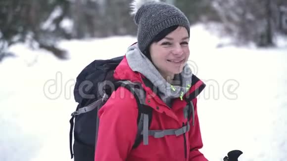 年轻的白种人妇女在白雪覆盖的树林里徒步旅行回头看视频的预览图