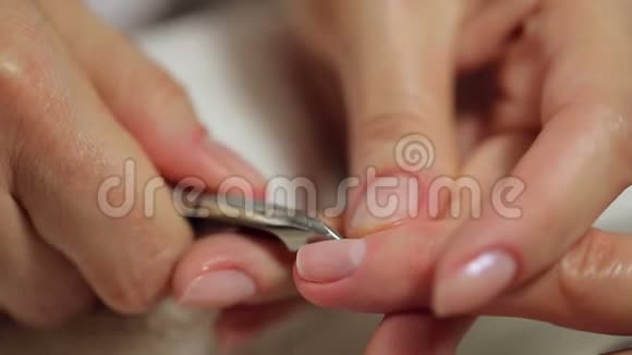 美甲师用指甲剪去女性指甲角质层的特写视频的预览图