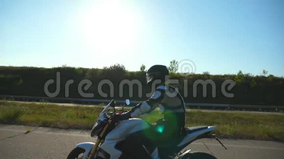 骑摩托车的人日落时分骑摩托车的人在乡间公路上驾驶摩托车慢动作侧视图视频的预览图