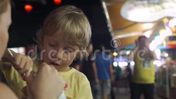 亚洲夜市上的小男孩吃手工制作的冰淇淋视频的预览图
