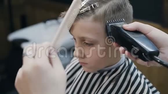 理发店里的理发师和可爱的客户孩子理发店使用修剪机和梳子漂亮可爱的孩子视频的预览图