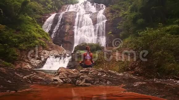 女孩在湖边做瑜伽姿势对抗水上瀑布视频的预览图