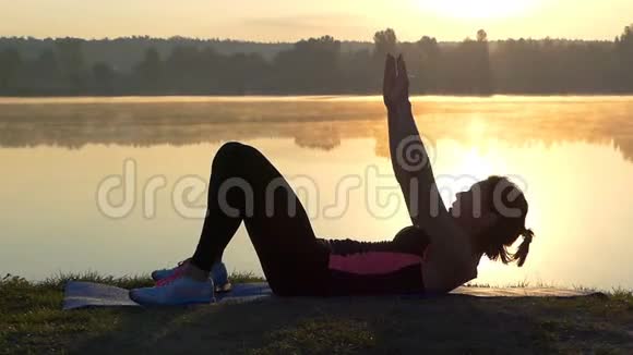 苗条的女人躺在湖边日落时抬起头视频的预览图