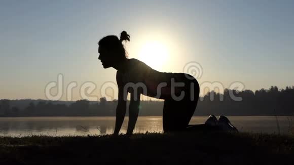 年轻女子在夕阳西下做猫瑜伽运动视频的预览图