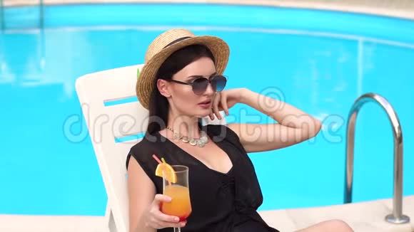 坐在泳池边喝鸡尾酒的少女视频的预览图