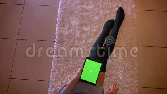 在室内地毯上用可爱的袜子特写了可爱的少女腿的肖像坐在地板上的女性视频的预览图