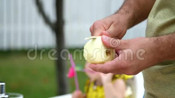 夏天在花园里慢动作特写男人的手用刀削苹果皮削果皮视频的预览图
