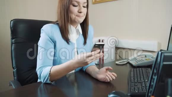 办公室里穿着蓝色夹克的快乐黑发女商人接电话视频的预览图