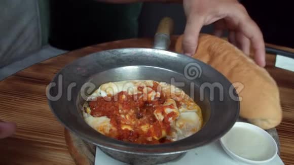 用手吃沙丘卡煮鸡蛋配番茄和面包放在煎锅里以色列阿拉伯中东视频的预览图