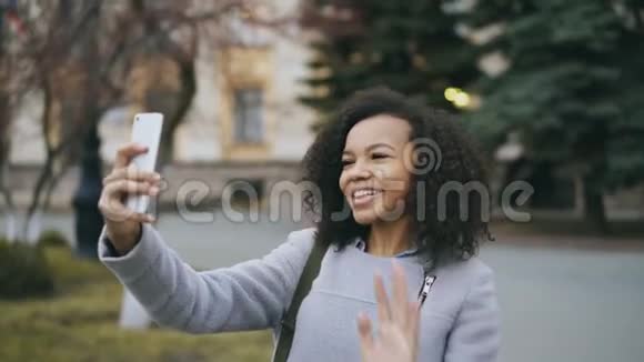 在大学附近用智能手机进行视频通话的混血女孩视频的预览图
