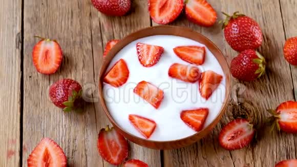木制碗里的草莓酸奶在桌子上旋转视频的预览图