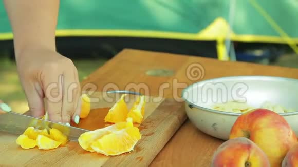 一个年轻的女人正在木板上编织一个橘子做水果沙拉视频的预览图