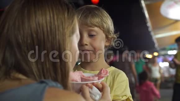 亚洲夜市上的小男孩吃手工制作的冰淇淋视频的预览图